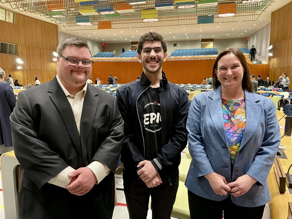 A photo of Tim Cologon, Mateo, and Kathy Cologon standing together in the Trusteeship Council Chambers at the United Nations Headquarters, New York
