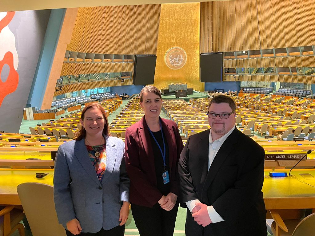 A photo of Kathy Cologon, Sheona McKenna, and Tim Cologon in the General Assembly at the United Nations Headquarters in New York